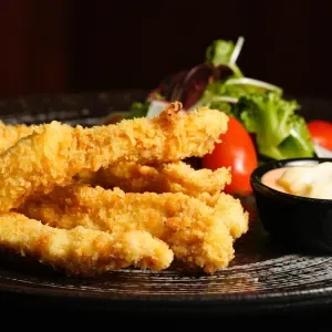 Deep fried chicken strips with salad, cocktail sauce